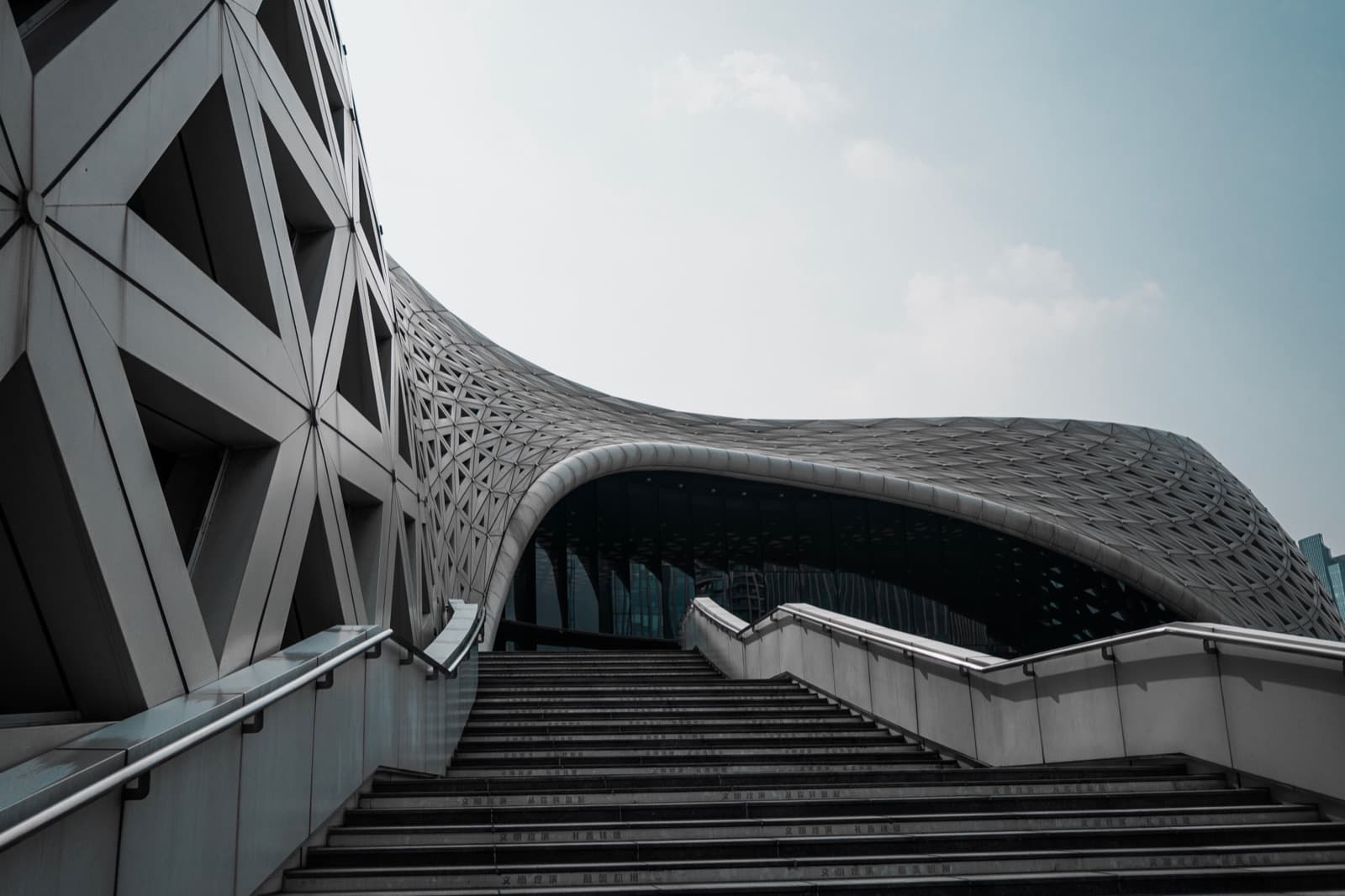 Modern building with a curved lattice facade above a wide staircase